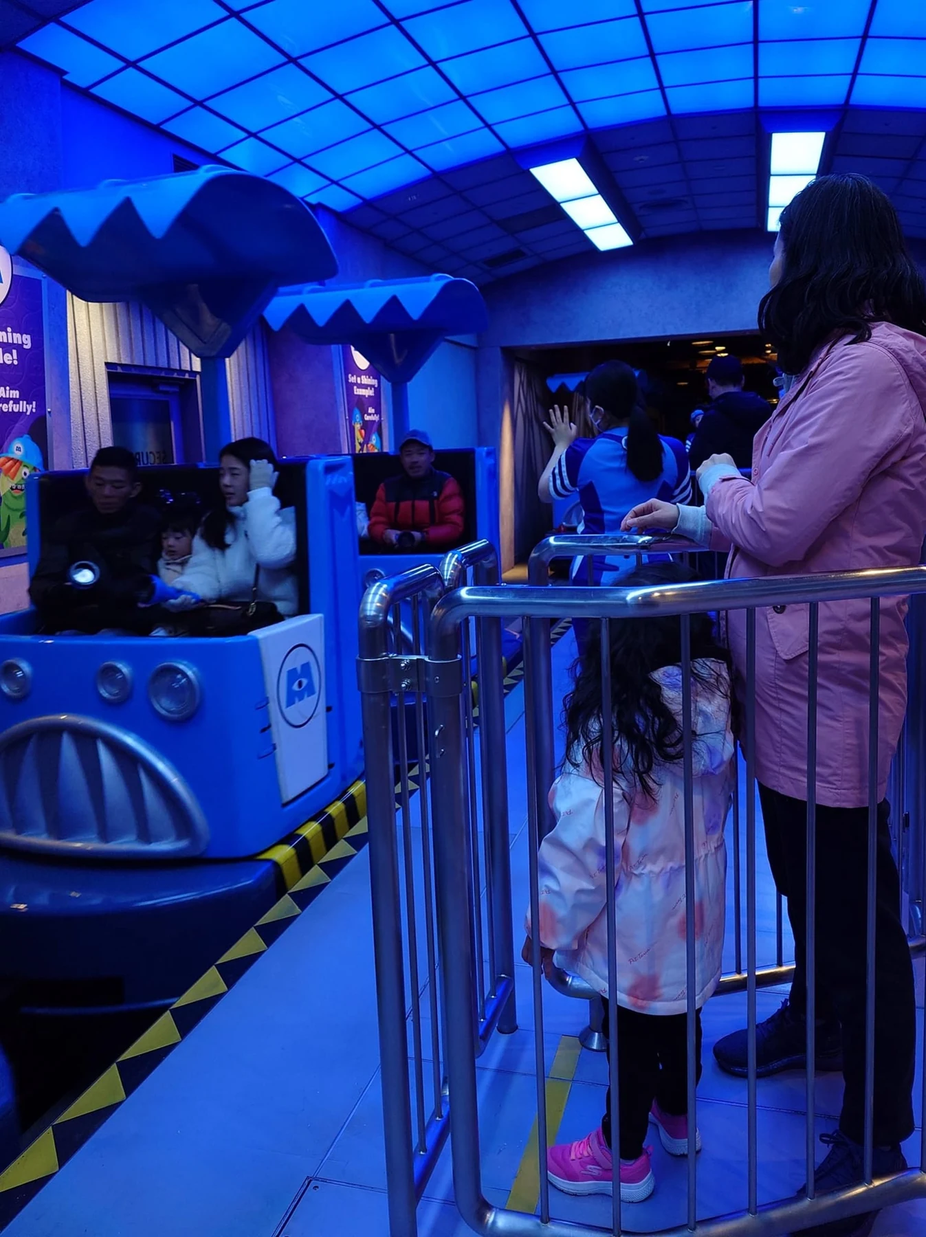 แม่และลูกยืนรอขึ้นรถของ Monsters, Inc. Ride & Go Seek!
