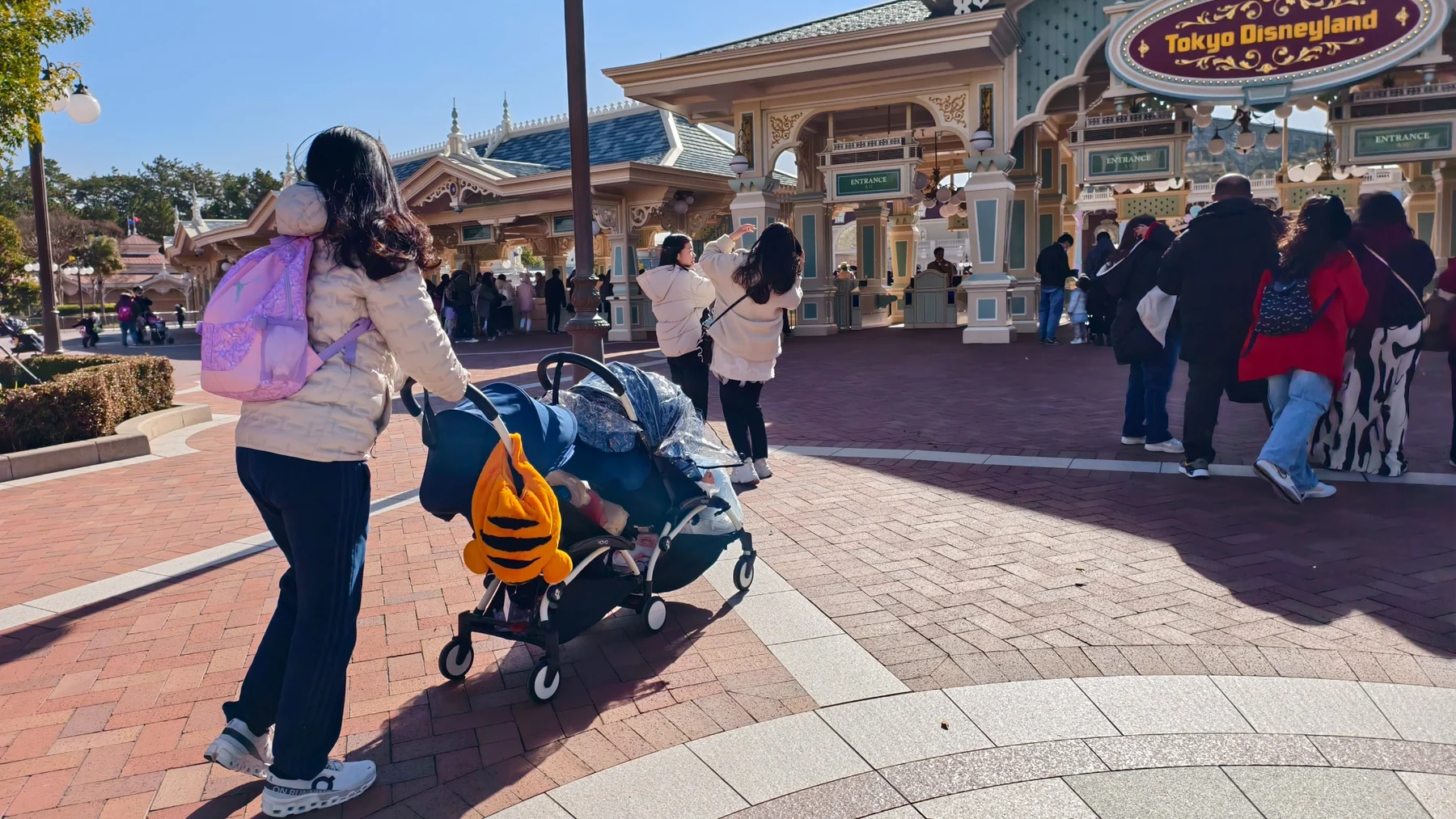 คุณแม่เข็นรถพาเด็ก ๆ เดินเข้าบริเวณทางเข้า Tokyo Disneyland