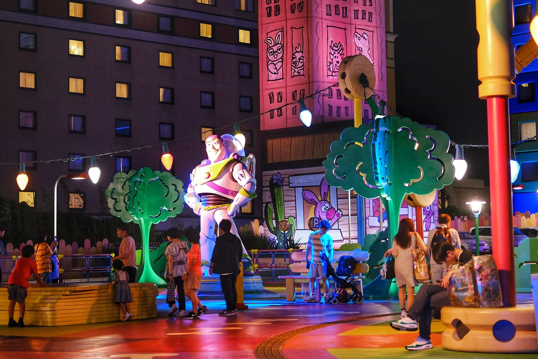 อาคาร Toy Story Hotel และรูปปั้น Buzz Lightyear ในลานช่วงค่ำ